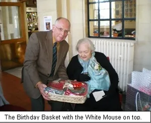 Nancy Wake receiving a birthday basket topped with a white mouse