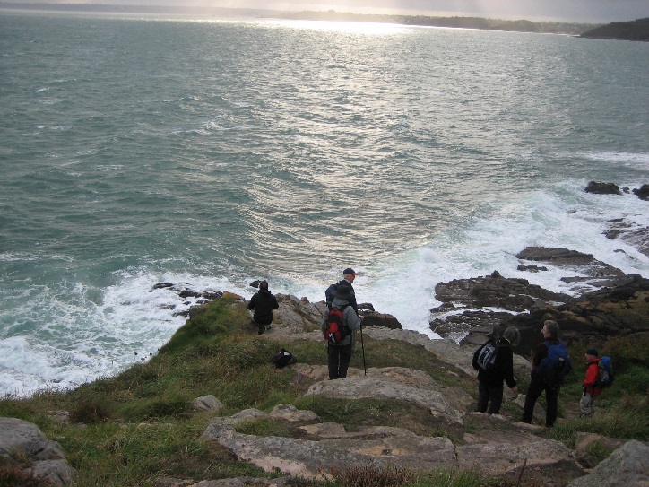 Walkers descending a rocky section of the Brittany coastal path
